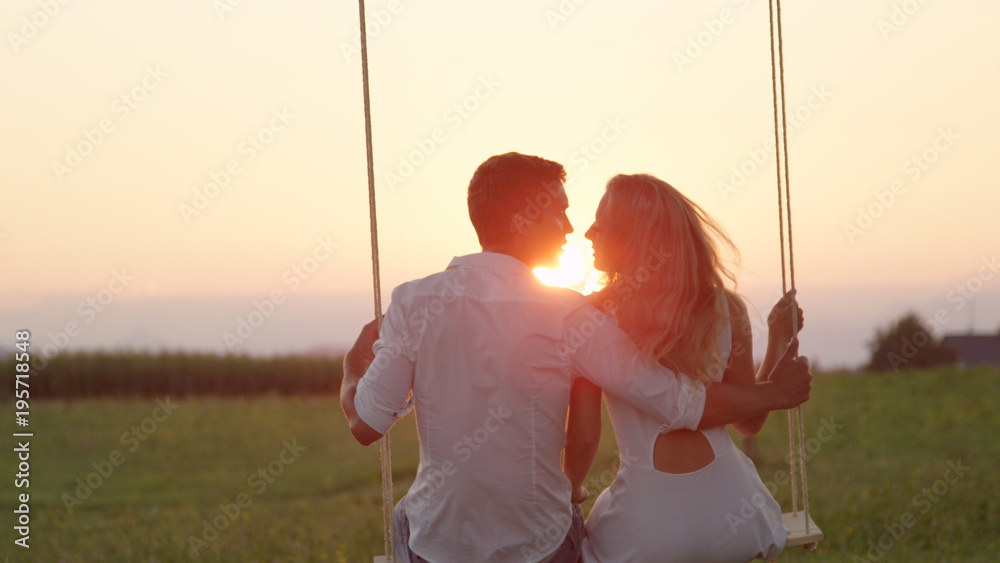 镜头特写：摇摆不定的年轻情侣在夏日日落时在树下接吻