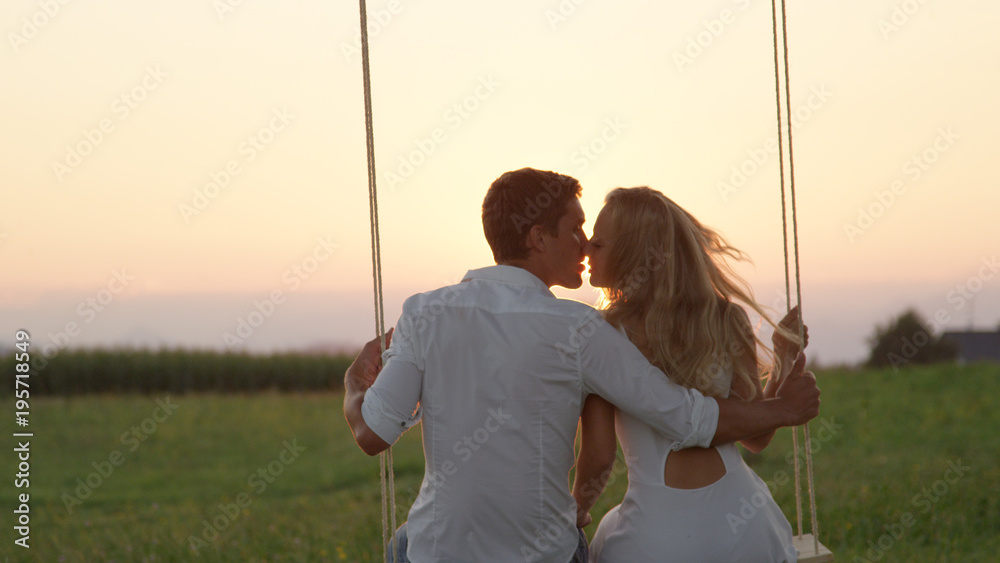 CLOSE UP: Joyous girlfriend and boyfriend kissing on summer evening in nature.