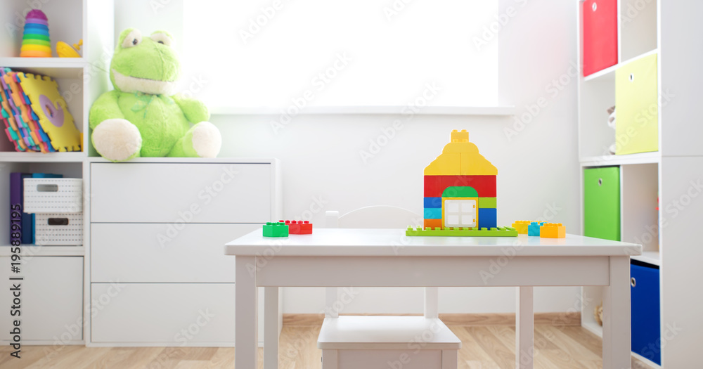 彩色儿童房，白色墙壁和家具。家里的彩虹地毯有风