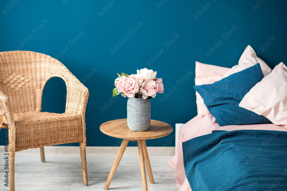 舒适的卧室内部碎片，蓝色墙壁背景上有花床和椅子