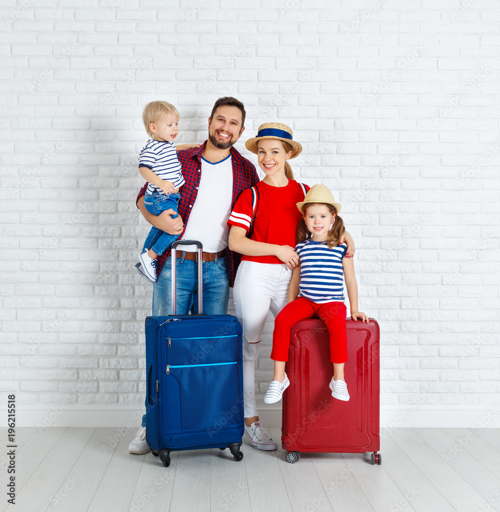 概念旅行和旅游。靠近墙壁带着行李箱的幸福家庭
