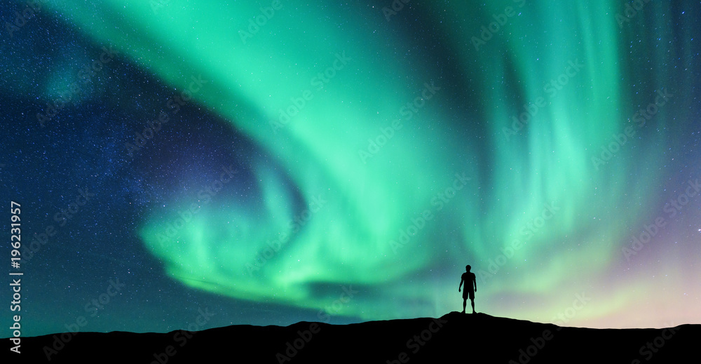 北极光和站着的人的剪影。挪威罗弗敦群岛。极光和快乐的人。天空w