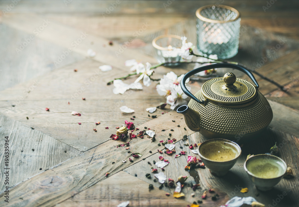 传统的亚洲茶道安排。铁茶壶、杯子、干玫瑰花蕾和木头上的蜡烛