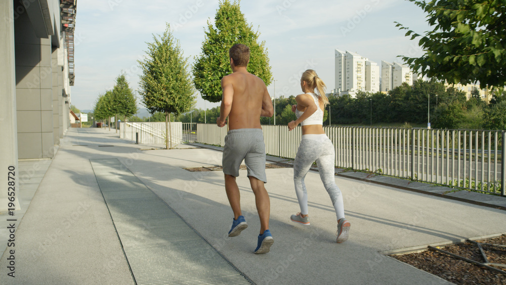 一对运动型的年轻夫妇在富裕的街区沿着宁静的大道奔跑。