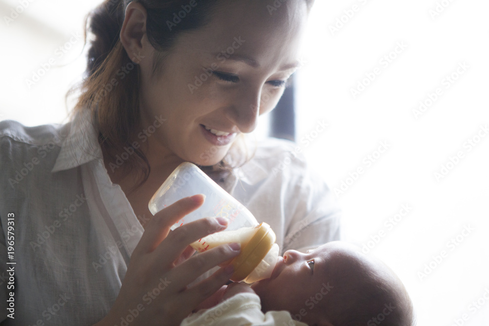 母親が哺乳瓶で子供にミルクを与えている