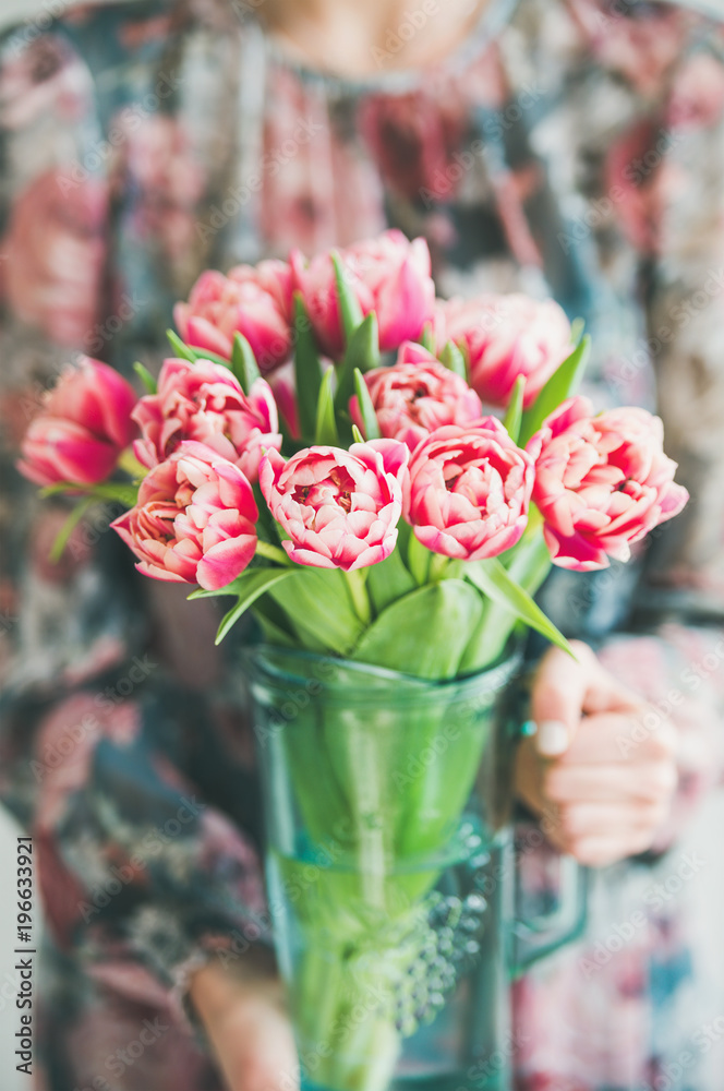 春季插花。穿着五颜六色丝绸连衣裙的女人手里拿着一束新鲜的粉红色郁金香。弗洛里