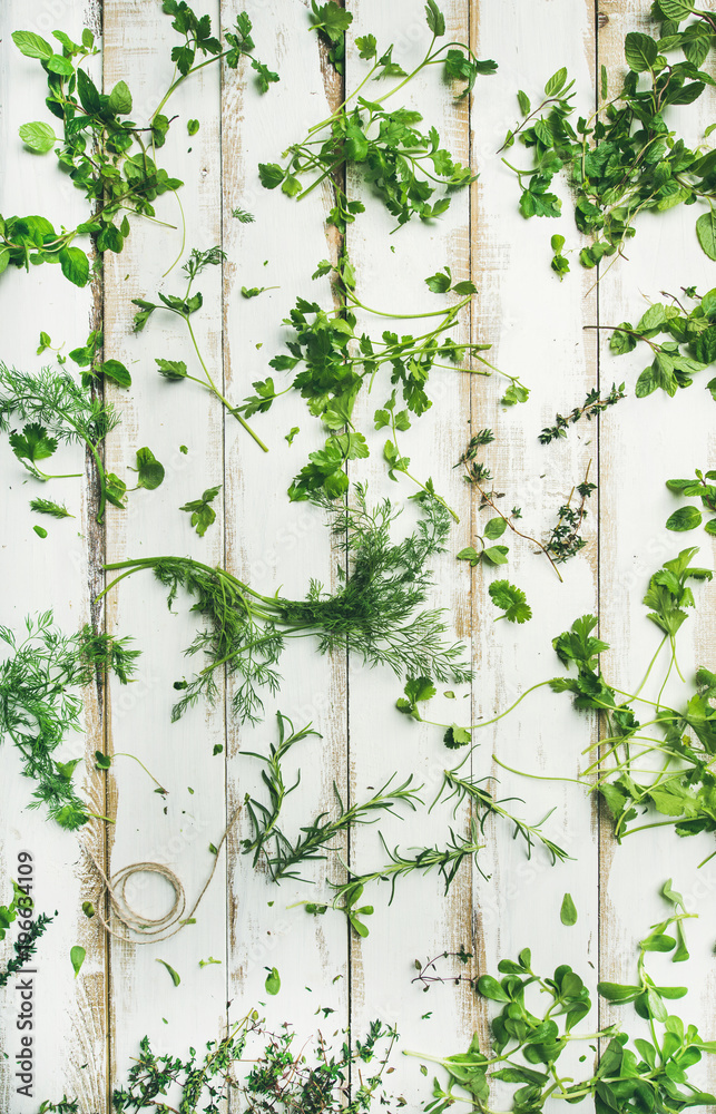 Flat-lay of various fresh green herbs. Parsley, mint, dill, cilantro, rosemary, thyme over white woo