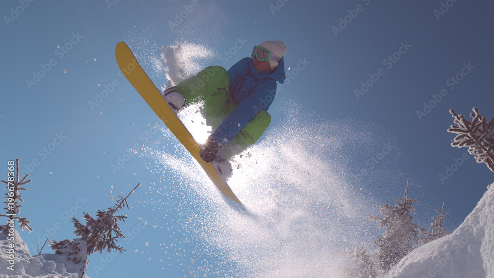 特写：职业单板滑雪运动员起飞，在遮挡阳光的同时做了一个很酷的动作