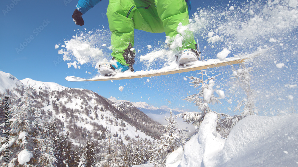 特写：一名滑雪运动员在空中跳跃，身后留下了一道新鲜的雪。