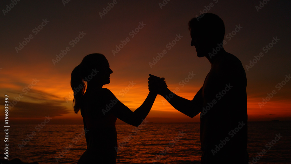 特写：一对在日落中微笑的快乐情侣在锻炼后握手