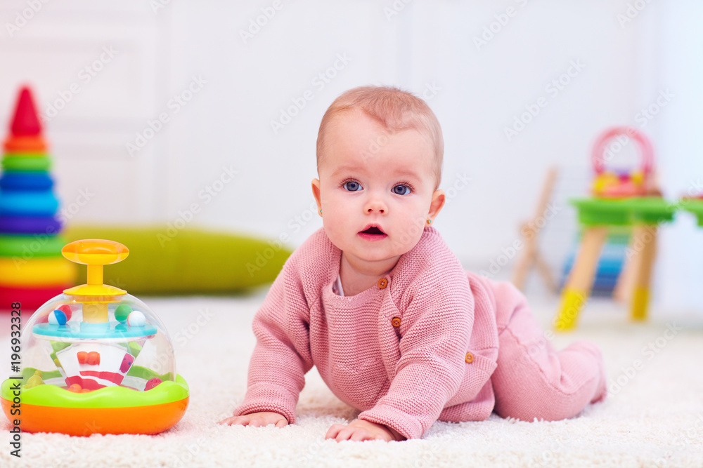 开发玩具中在地毯上爬行的可爱小女婴