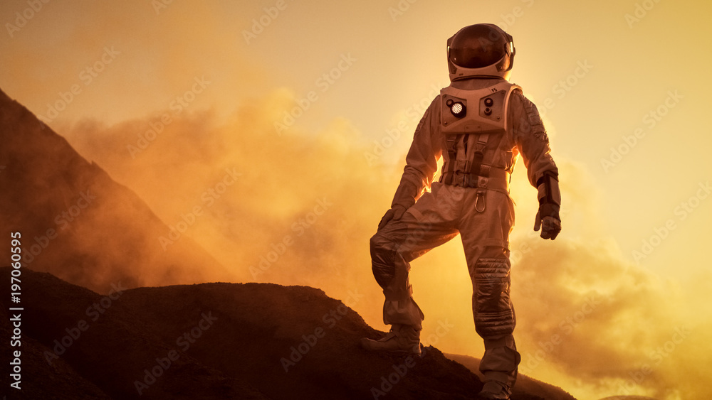 站在外星红色星球/火星落基山上的宇航员剪影。第一个人