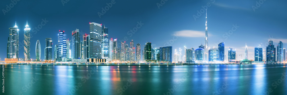 Dubai skyline after sunset with beautiful city center lights reflection and promenade around the can
