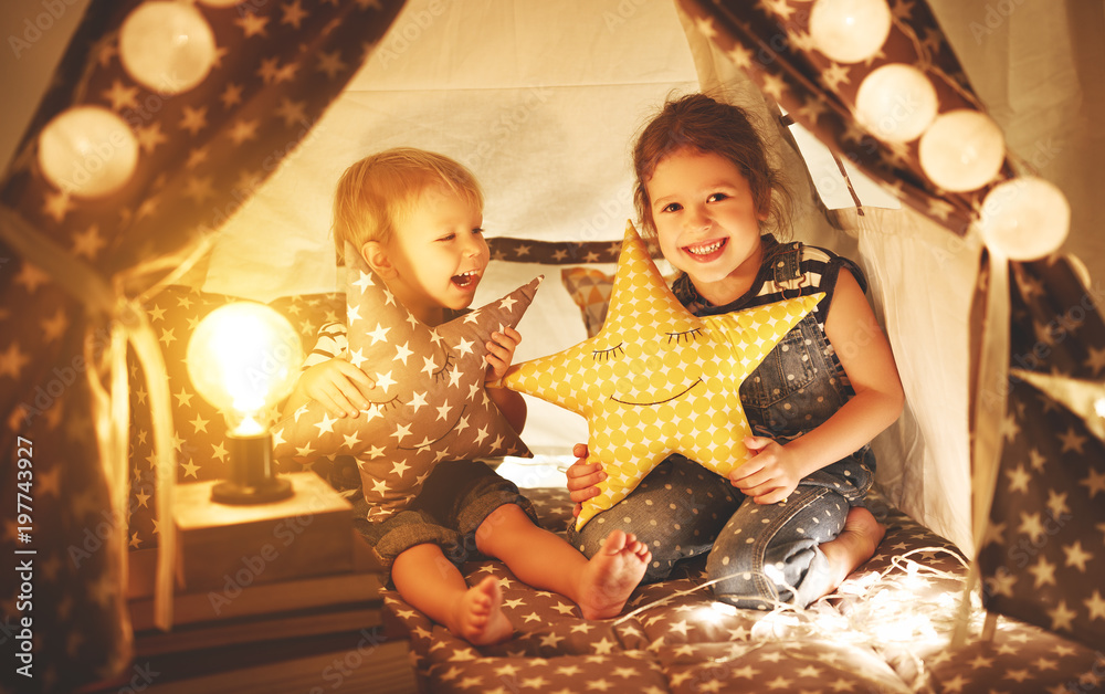 快乐家庭的孩子兄弟姐妹在游戏室的黑暗帐篷里玩耍、大笑和拥抱