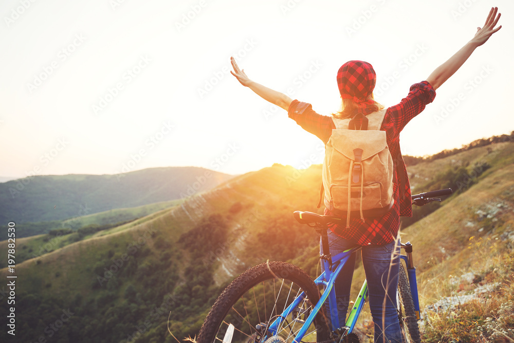 夏季户外徒步旅行日落时骑自行车在山顶的女游客