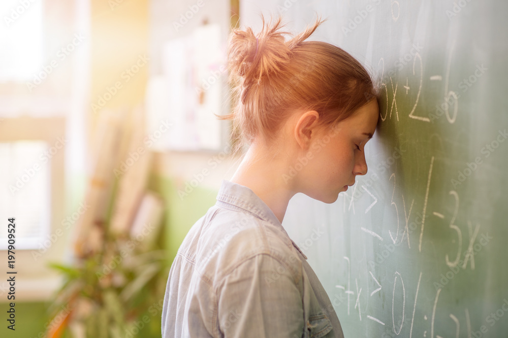 数学课上的少女被数学公式淹没了。压力、教育、成功的概念。