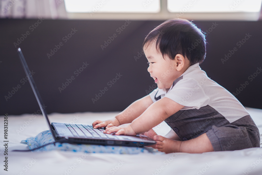 Asian baby in business suite sit and play computer notebook