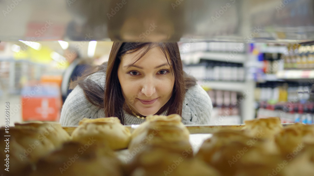 店里面包烘焙部的一位深色女人挑选新鲜馅饼