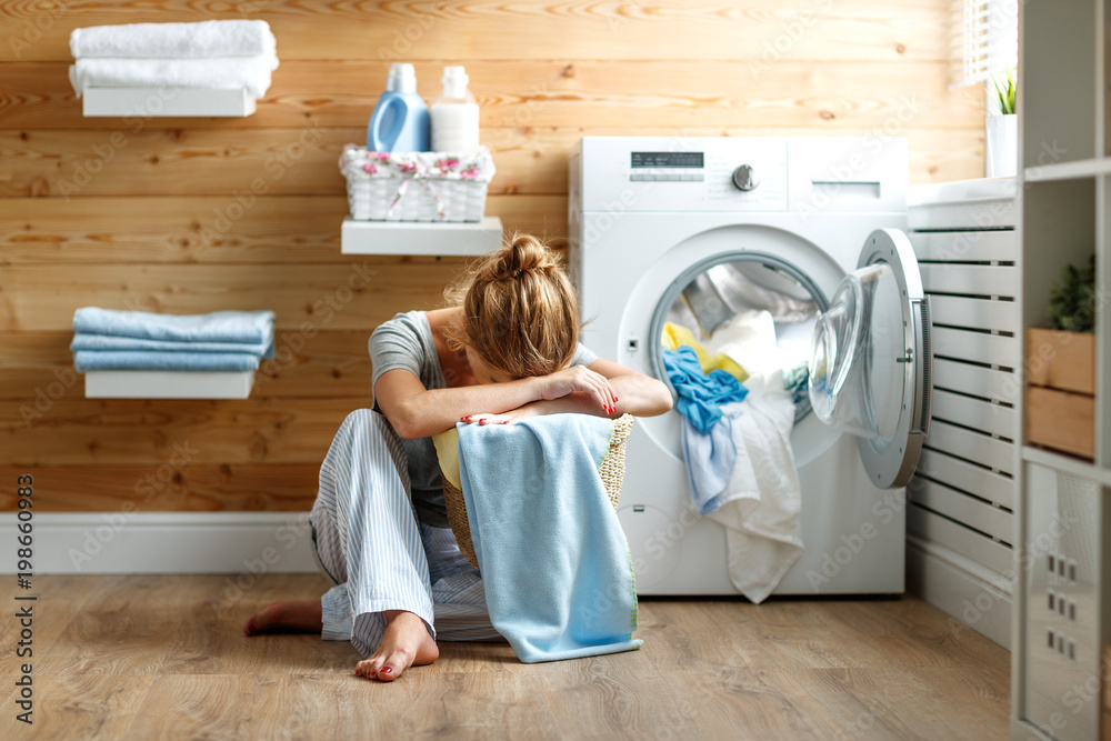 疲惫的家庭主妇，压力重重，睡在带洗衣机的洗衣房里