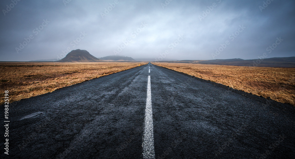 A road leading to distance at cloudy day with mountains in the background