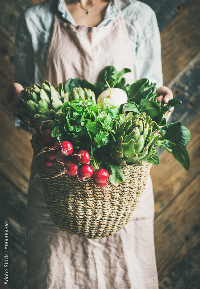 穿着亚麻围裙的女农民手里拿着一篮子新鲜的花园蔬菜和绿色蔬菜，锈迹斑斑
