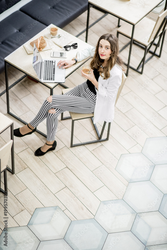 一位商务女性的肖像，坐在现代咖啡馆内部的咖啡休息时间，俯视图