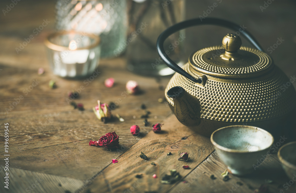 传统的亚洲茶道安排。金色的铁茶壶、杯子、干玫瑰、葡萄酒上的蜡烛