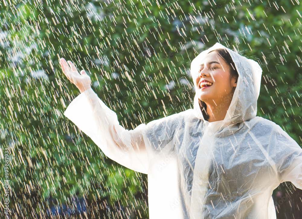 雨天，一个在户外穿着雨衣的亚洲女人。她很开心。