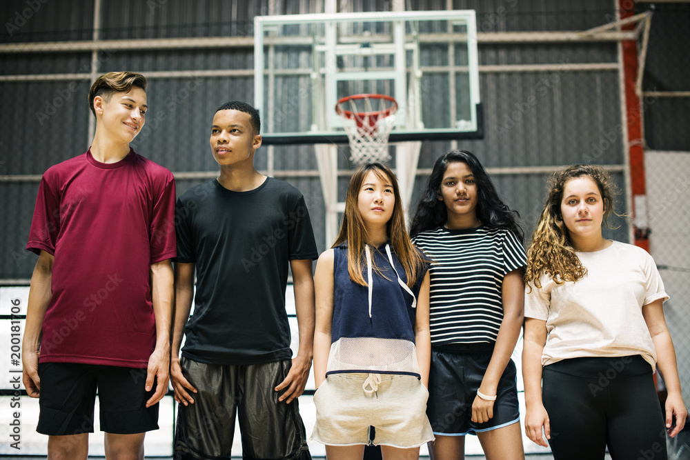 一群年轻的青少年朋友站在篮球场上，排成一排