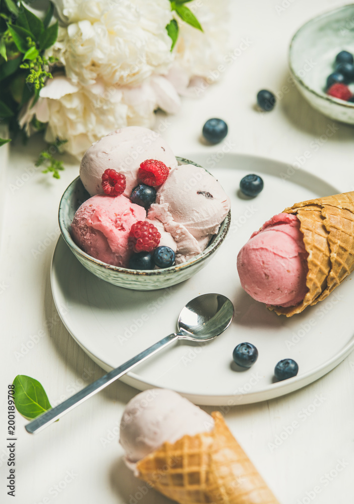 碗里的粉红色草莓和椰子冰淇淋勺、甜甜筒、牡丹花和新鲜b