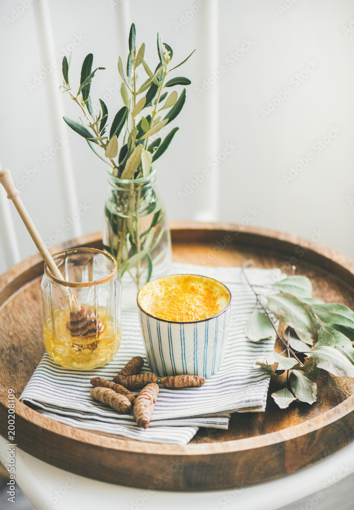 健康素食姜黄拿铁或金黄色牛奶，装在木托盘上的杯子里