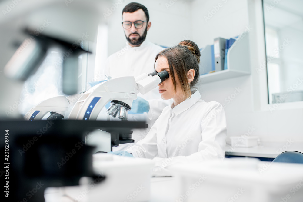 穿着制服的医生在实验室办公室进行显微镜分析