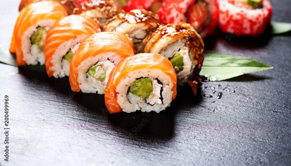 寿司卷特写。餐厅里的日本食物。卷上三文鱼、鳗鱼、蔬菜和飞鱼