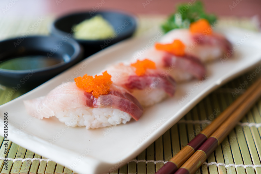 白色盘子上的滨池寿司，配日本酱汁和绿叶装饰，日本食品，clo