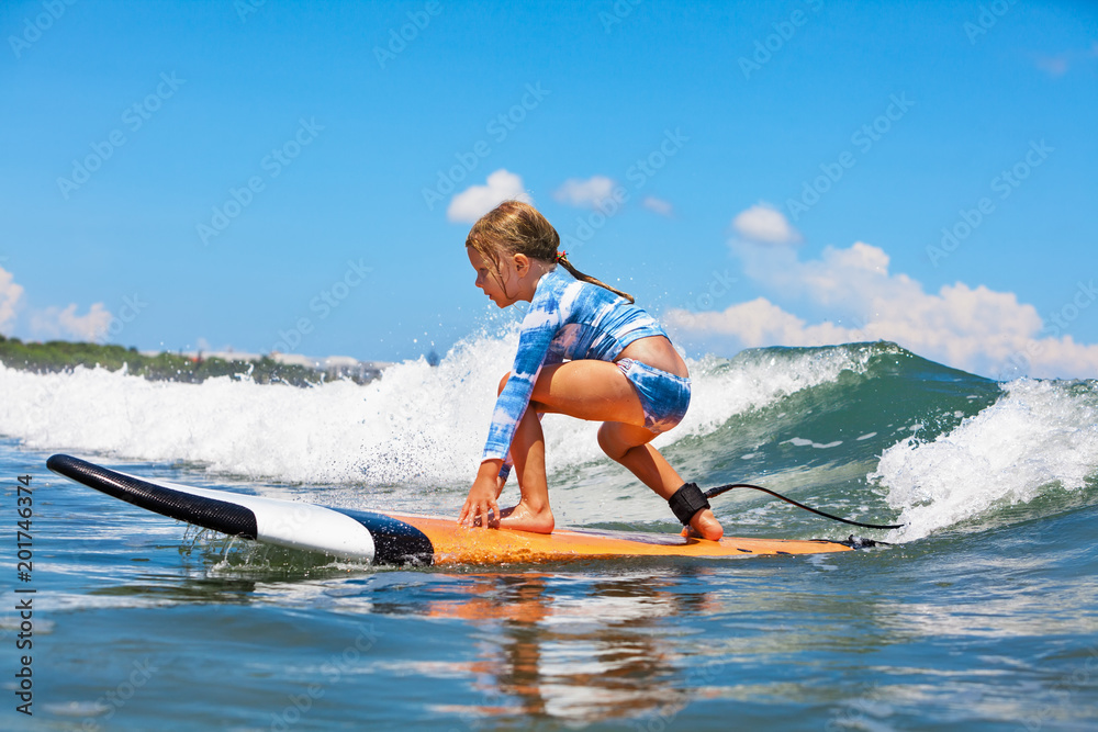 快乐的女婴-年轻的冲浪者在冲浪板上冲浪，在海浪上玩得很开心。孩子，积极的家庭生活方式