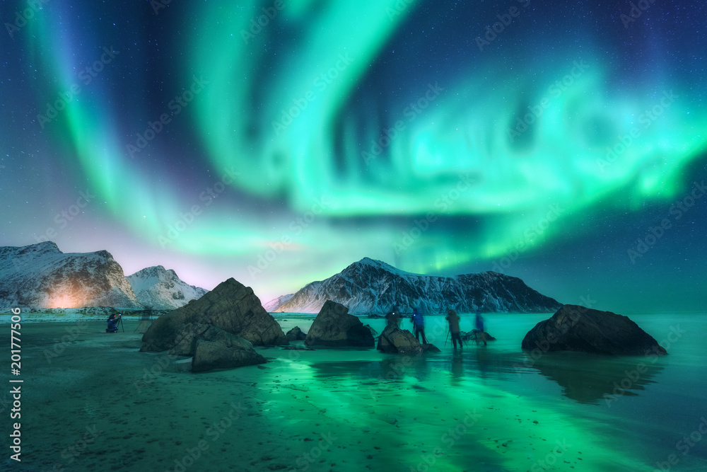绿色北极光和摄影师。极光。挪威罗弗敦群岛的北极光。星空