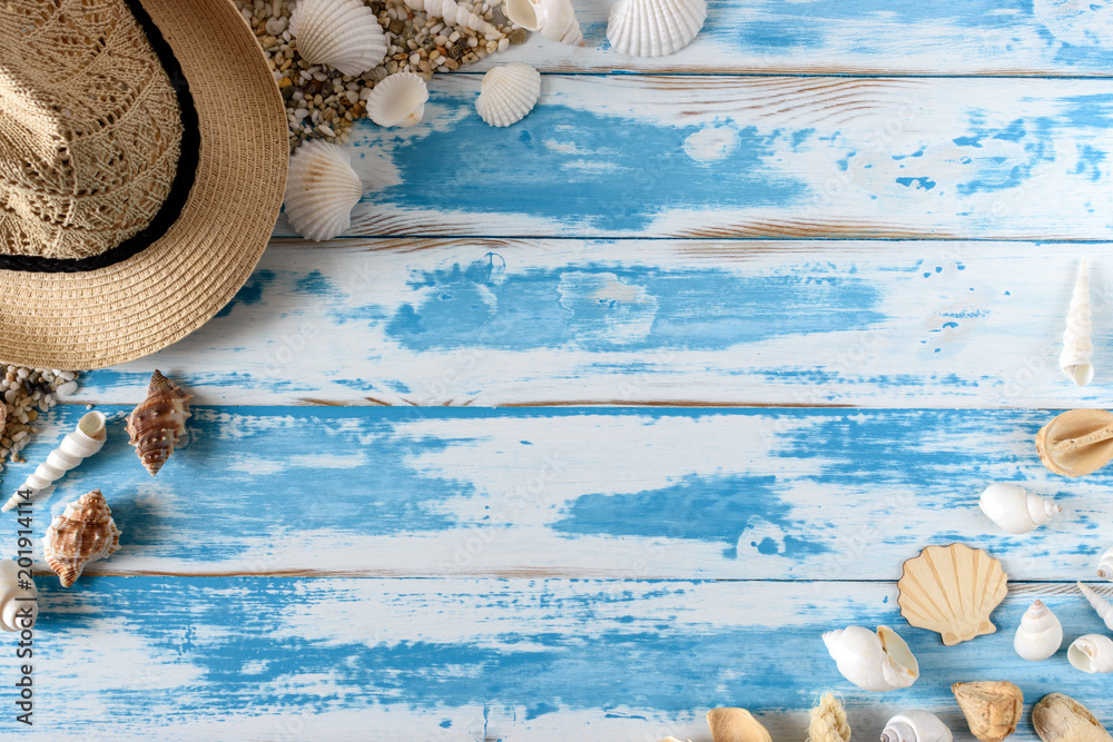 蓝色木板上的贝壳，带草帽。暑假背景。