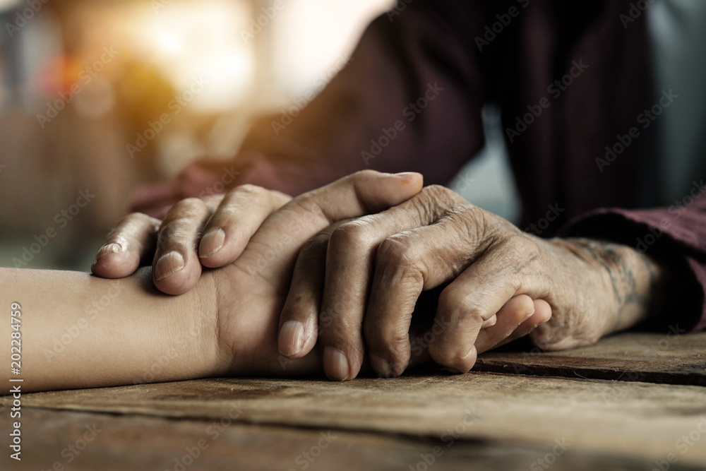 老人和孩子的手放在木桌上