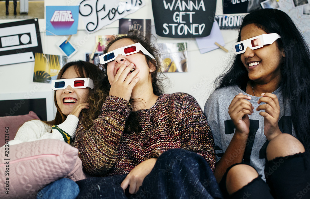 戴着3d电影眼镜的少女们享受着欢笑和看电视