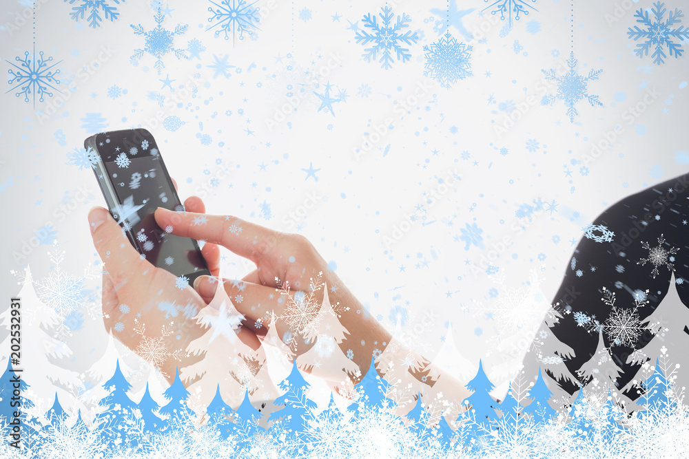 一位女士在雪花和冷杉树上使用智能手机的合成图像