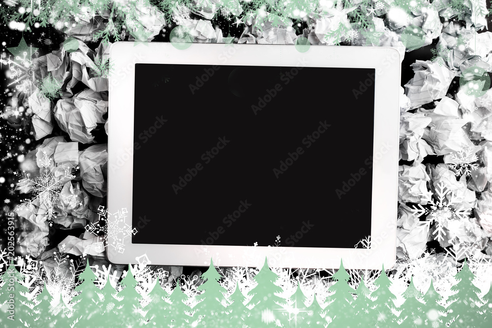 Composite image of tablet screen against snowflakes and fir trees in green