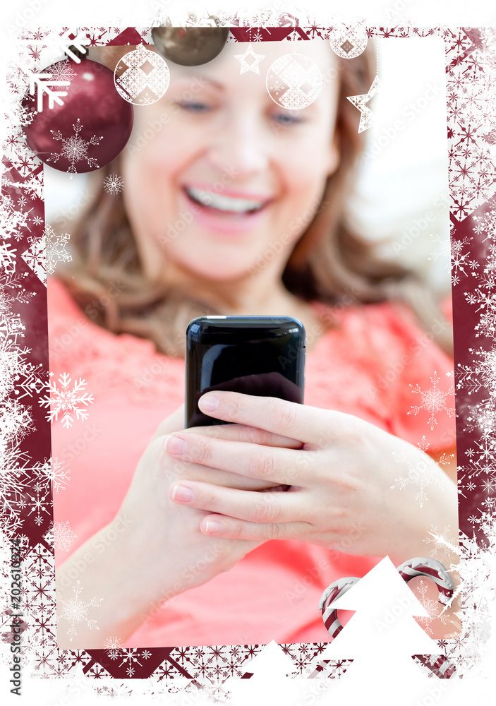 笑着的女人躺在沙发上对着圣诞主题框架发短信
