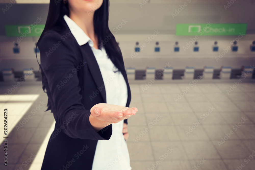 Pretty businesswoman presenting with hand against airport
