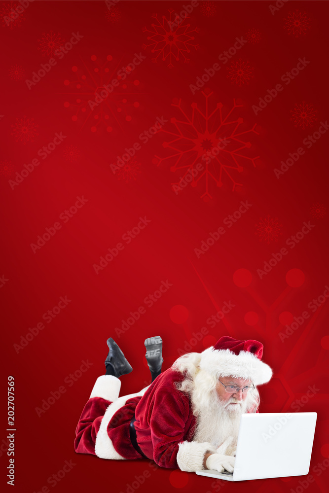 圣诞老人躺在红色背景下的笔记本电脑前