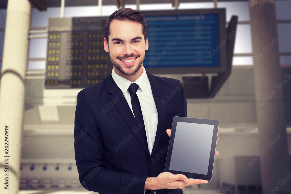 微笑的商人对着机场展示他的平板电脑