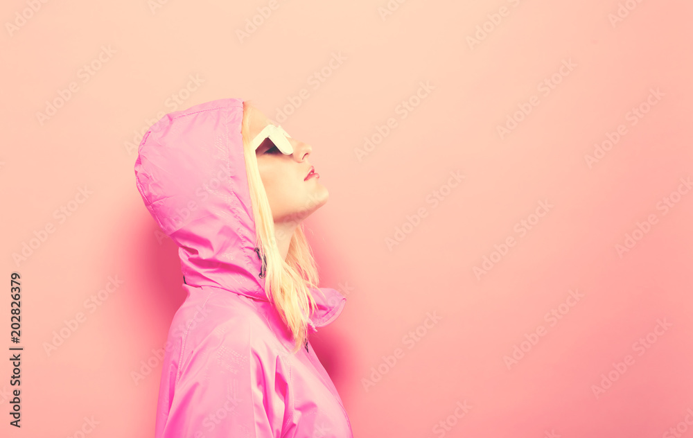穿着粉色雨衣，戴着粉色背景墨镜的时尚女性