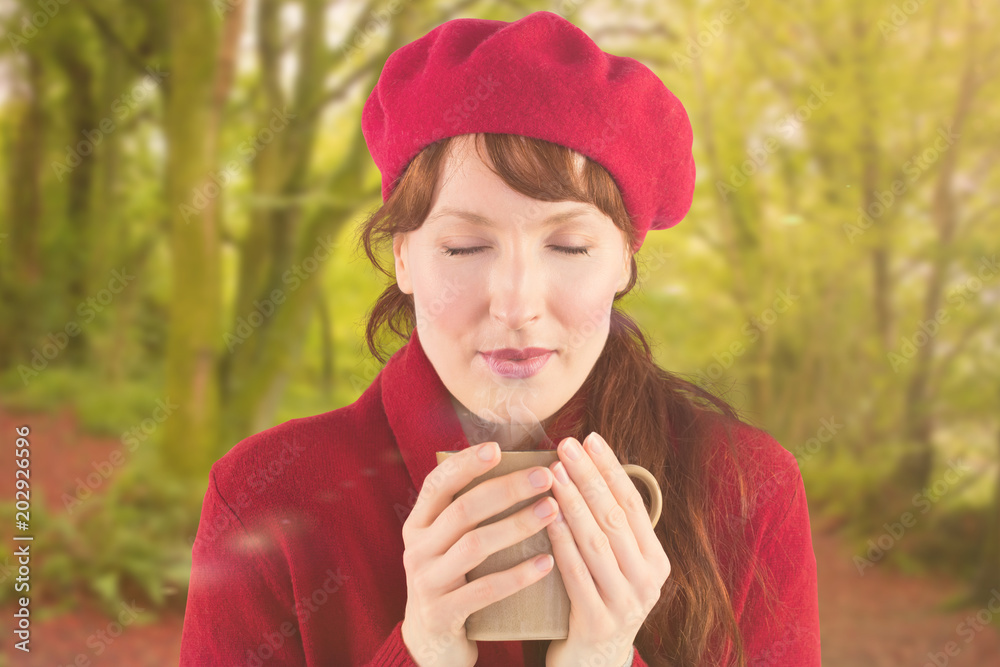 女人拿着一个温暖的杯子对着森林里平静的秋景