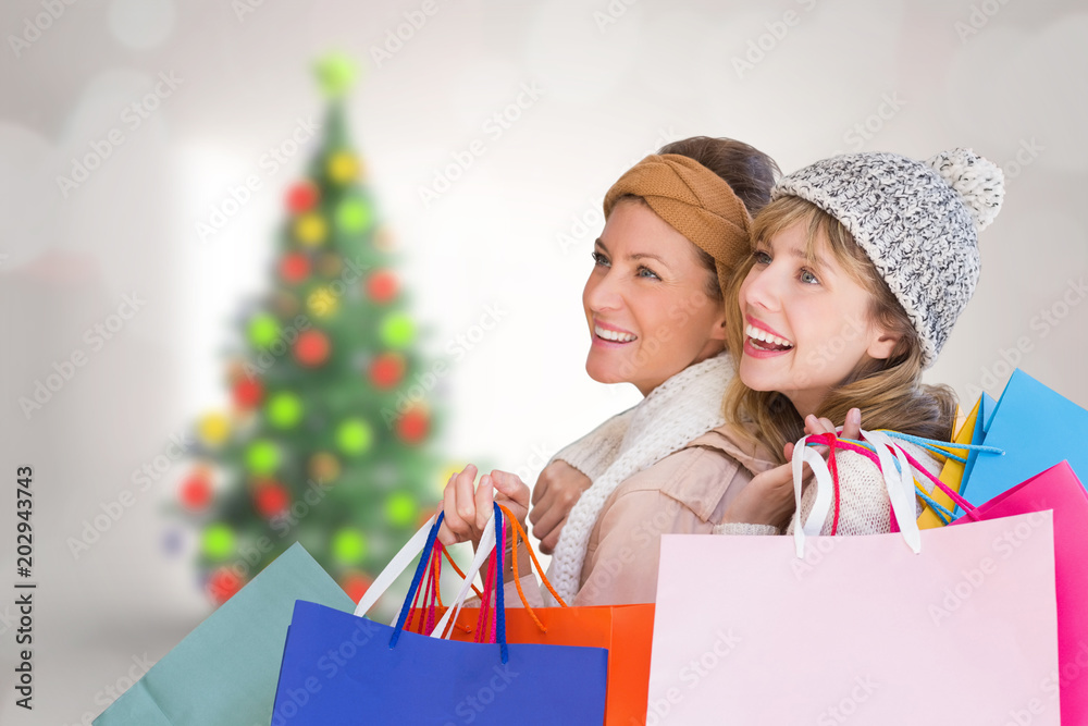 美丽的女人拿着购物袋，看着房间里模糊的圣诞树