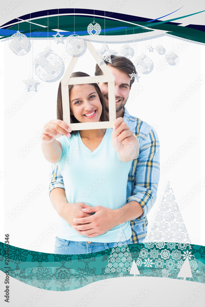 幸福的年轻夫妇，房子的形状与圣诞框架相映衬