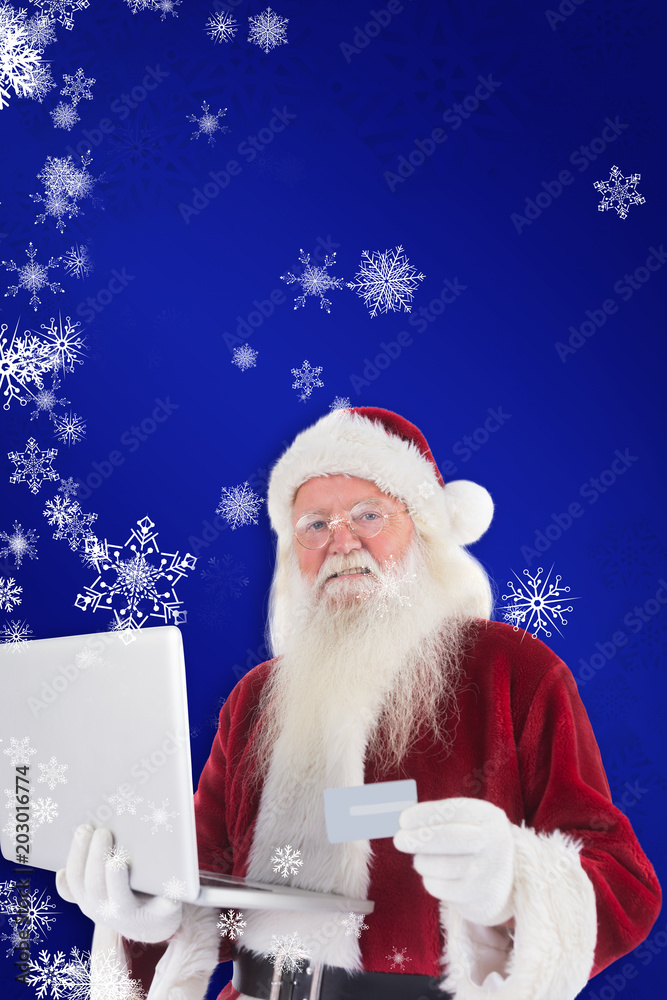 圣诞老人在蓝色背景下用笔记本电脑上的信用卡付款